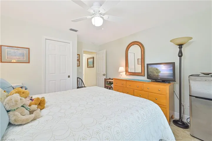 Bedroom featuring freestanding refrigerator, a ceiling fan, and a closet