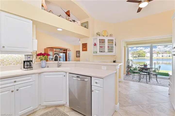 Kitchen featuring ceiling fan, white cabinetry, dishwasher, glass insert cabinets, and light tile patterned flooring