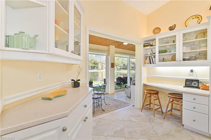 Kitchen with glass fronted cabinets, white cabinetry, a breakfast bar, and open shelves