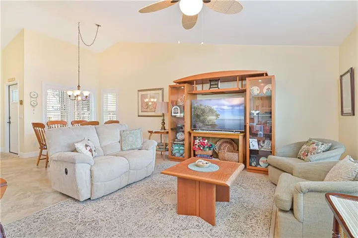 Living area featuring a ceiling fan, vaulted ceiling, and a chandelier