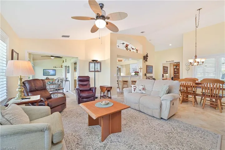 Living room with lofted ceiling, a ceiling fan, and a chandelier