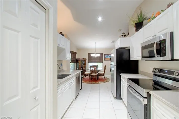 Kitchen with stainless steel appliances, pendant lighting, white cabinets, and light countertops