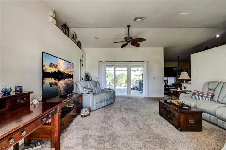 Living area featuring carpet, ceiling fan, and vaulted ceiling