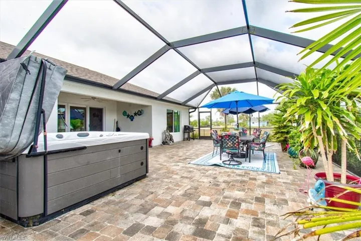 View of patio featuring a hot tub, a ceiling fan, a sunroom, and a lanai
