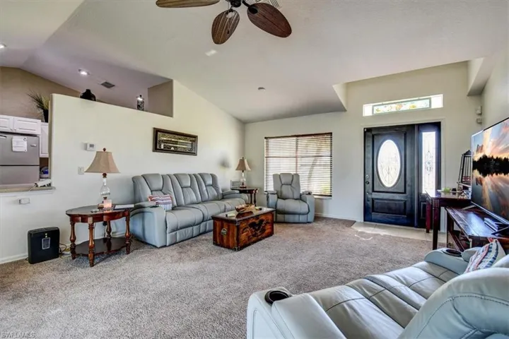 Living area featuring carpet floors, lofted ceiling, and a ceiling fan