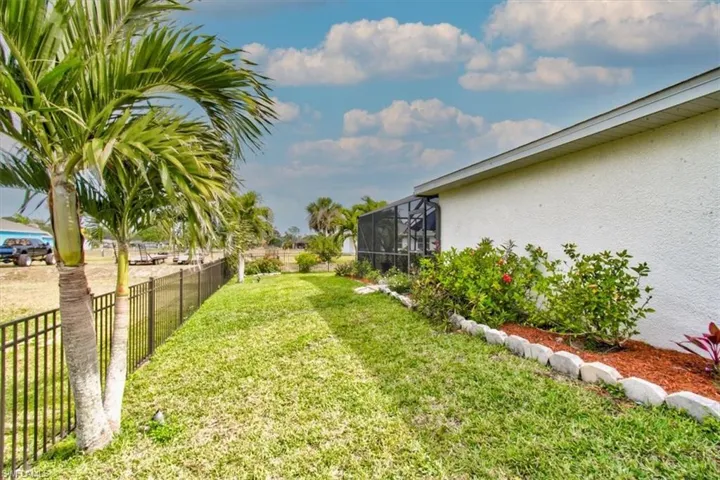 Fenced backyard featuring a sunroom and a lanai