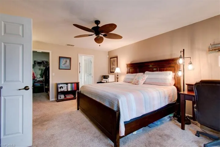 Bedroom with light carpet, a spacious closet, and a ceiling fan