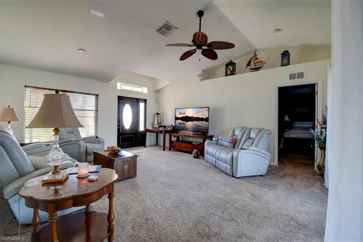 Living area featuring carpet floors, lofted ceiling, and a ceiling fan