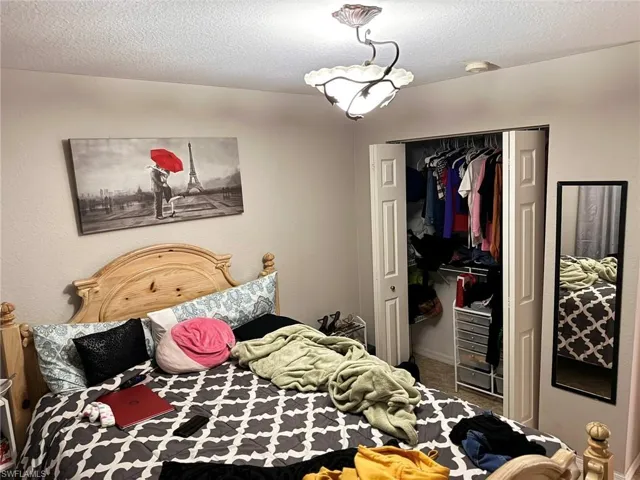 Carpeted bedroom featuring a textured ceiling and a closet