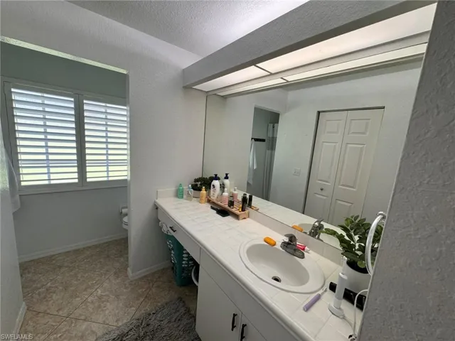 Bathroom featuring tile patterned floors, vanity, a textured ceiling, and toilet
