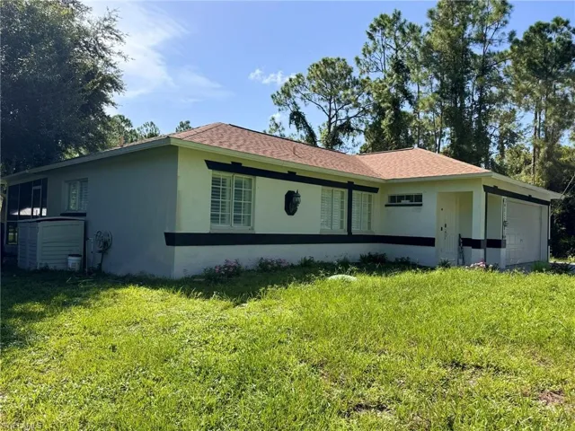Back of house featuring a garage and a lawn