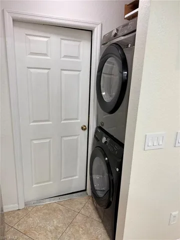 Washroom featuring stacked washer and dryer and light tile patterned floors
