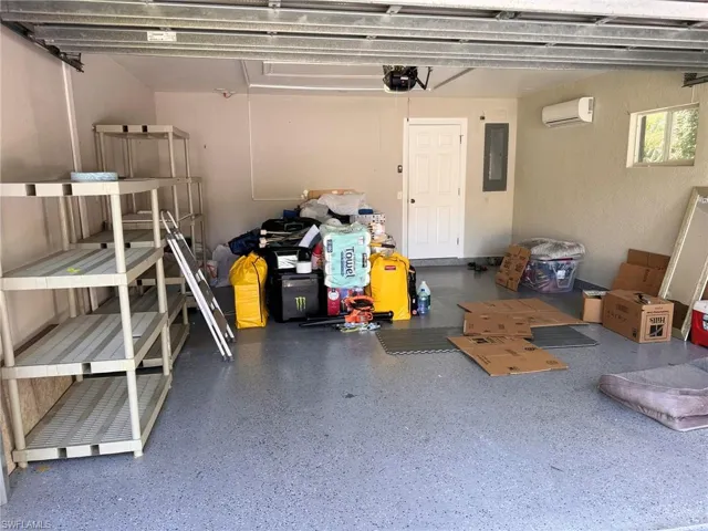 Garage with electric panel, a garage door opener, and a wall mounted AC