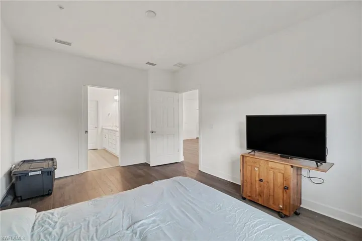 Interior room featuring dark wood-finish flooring, white walls, and bright overhead lighting