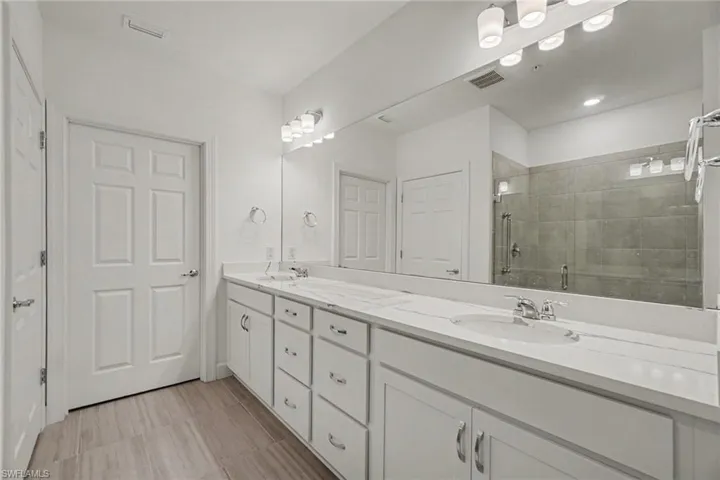 Double vanity with white cabinetry, integrated sinks, and a full-width mirror
