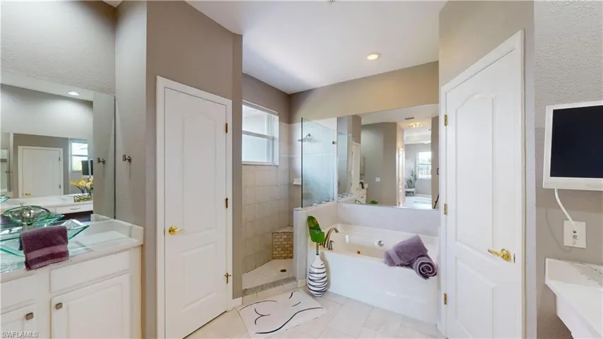 Full bath with vanity, a tub with jets, walk in shower, a closet, and recessed lighting