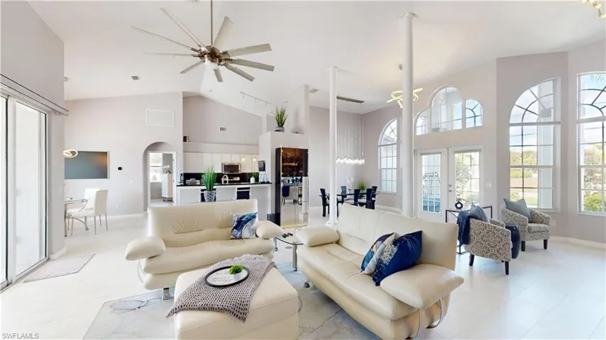 Living room with ceiling fan, french doors, arched walkways, and lofted ceiling