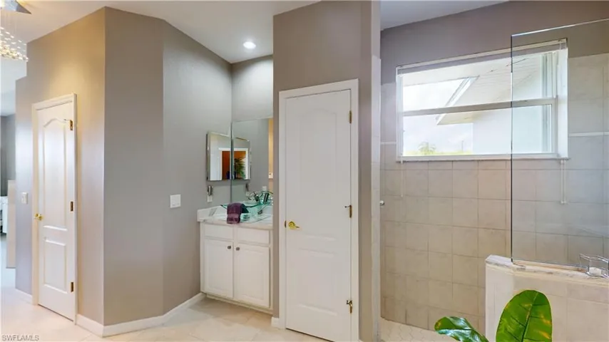 Full bath featuring walk in shower, vanity, and light tile patterned floors