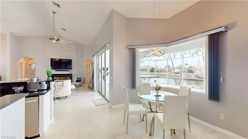 Dining room featuring ceiling fan, arched walkways, lofted ceiling, and a fireplace