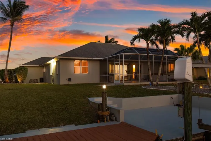 Rear view of house with a sunroom, glass enclosure, stucco siding, a yard, and a patio