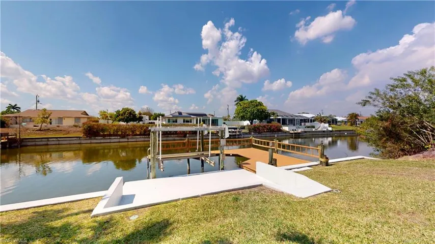 Dock with a yard, boat lift, a water view, and a residential view