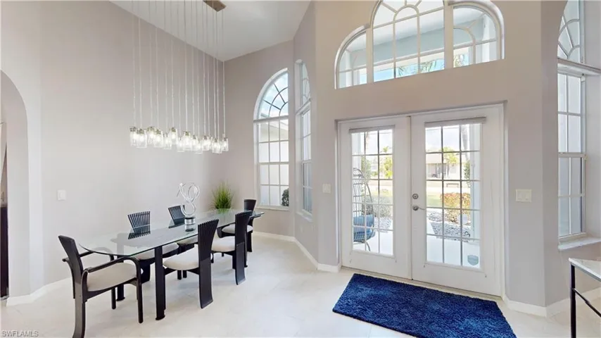 Dining room with arched walkways, french doors, and a high ceiling