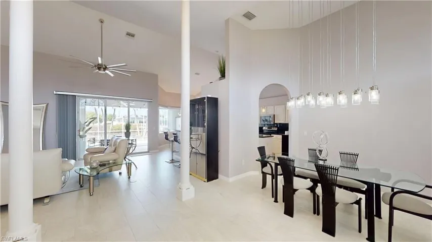 Dining area with a ceiling fan, vaulted ceiling, arched walkways, and ornate columns