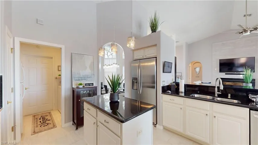 Kitchen with stainless steel refrigerator with ice dispenser, ceiling fan, dark stone counters, a high ceiling, and white cabinetry