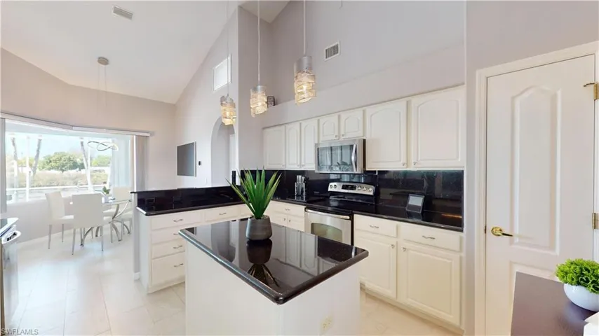 Kitchen featuring a center island, stainless steel appliances, lofted ceiling, a peninsula, and pendant lighting