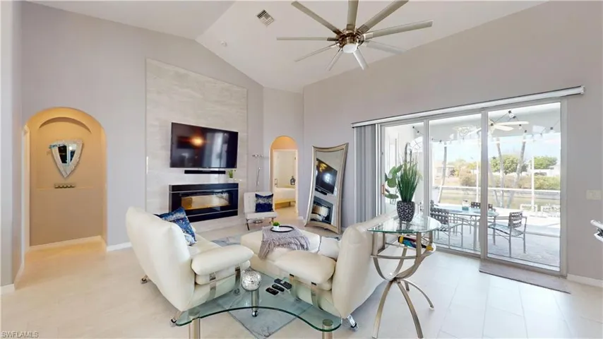Living room with a ceiling fan, arched walkways, vaulted ceiling, and a premium fireplace