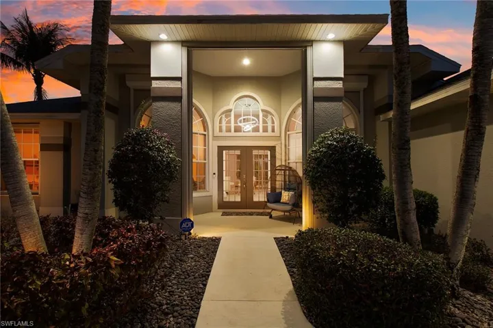 Exterior entry at dusk featuring french doors, stucco siding, and covered porch