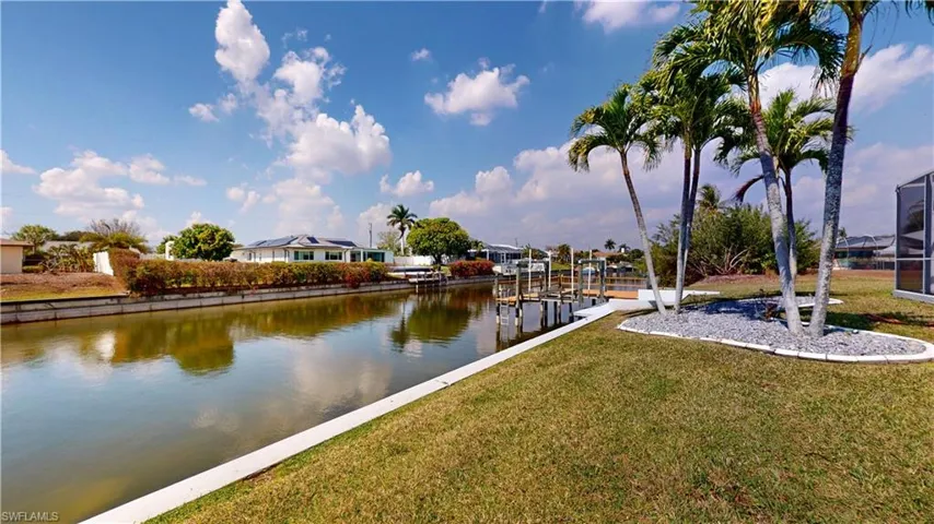 Water view with a boat dock, boat lift, and nearby suburban area