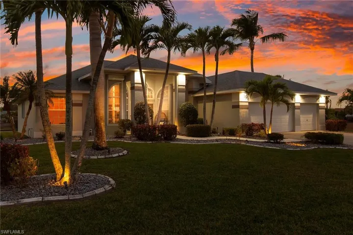 View of front of house featuring a garage, a yard, and stucco siding