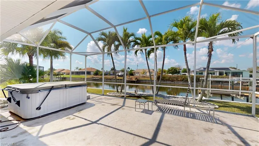 View of patio featuring a residential view, glass enclosure, a water view, a sunroom, and a hot tub