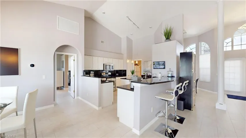 Kitchen featuring a kitchen breakfast bar, a peninsula, white cabinets, arched walkways, and stainless steel appliances