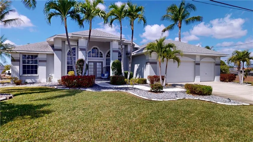 View of front of house with stucco siding, a garage, a front lawn, and driveway