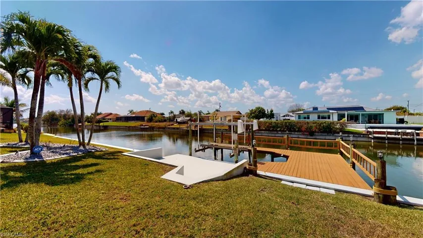 Dock featuring boat lift, a yard, a residential view, and a water view