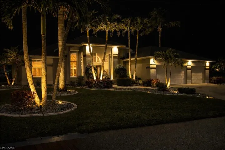 View of front facade featuring a garage, driveway, a yard, and stucco siding