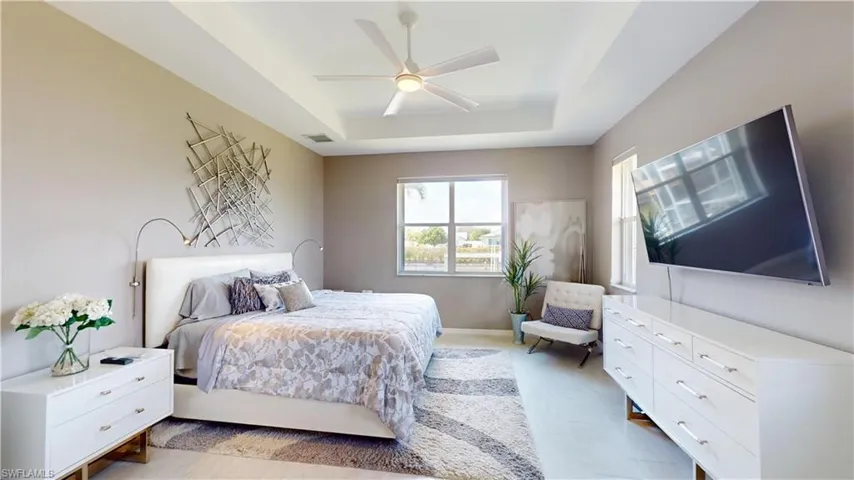 Bedroom featuring a tray ceiling, ceiling fan, and light wood-style flooring