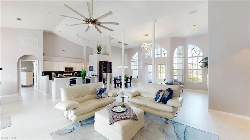 Living room with ceiling fan, arched walkways, and vaulted ceiling