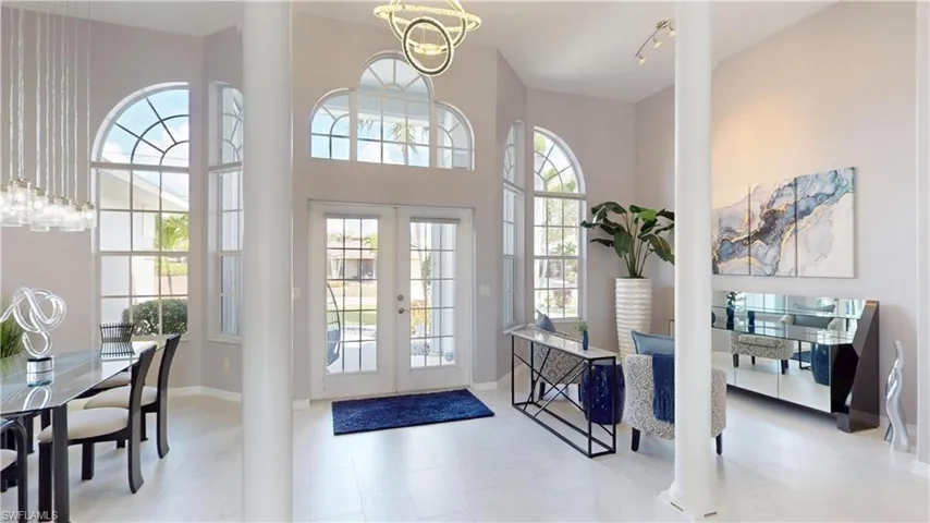 Entryway featuring french doors, a high ceiling, suspended lighting, and ornate columns