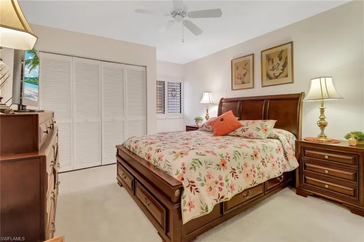 Bedroom with ceiling fan, light colored carpet, and a closet