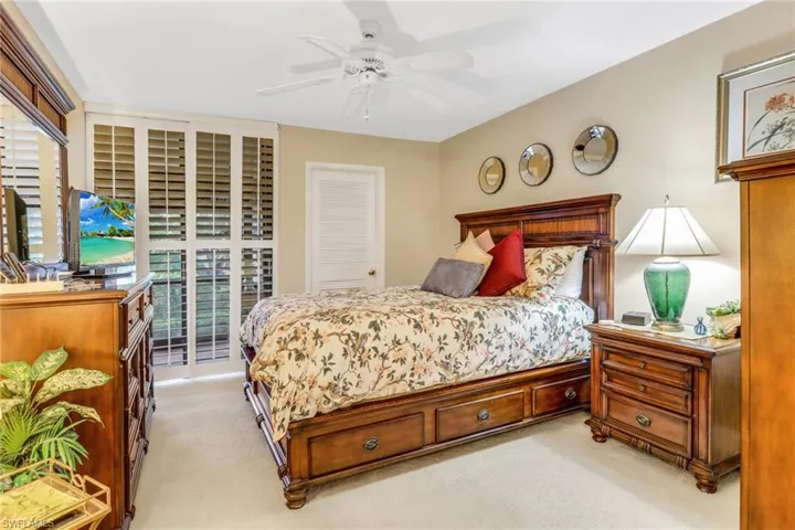 Bedroom with a closet, access to outside, light colored carpet, and ceiling fan