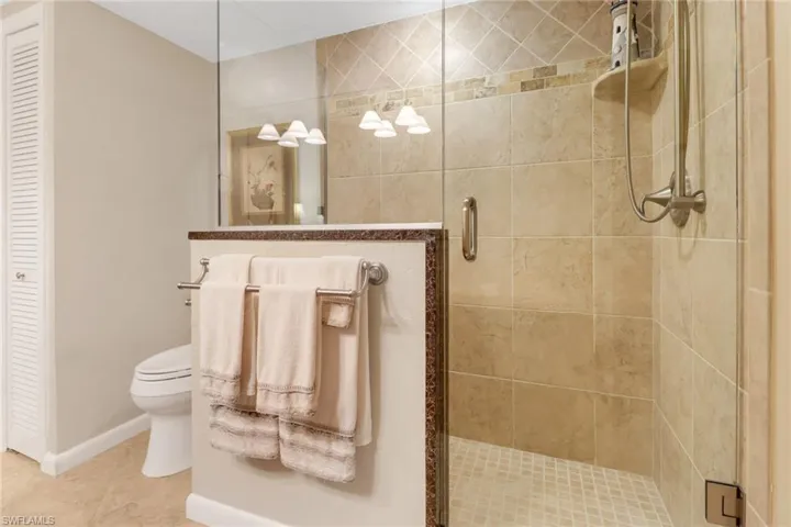 Bathroom with toilet, tile patterned flooring, and a shower with shower door