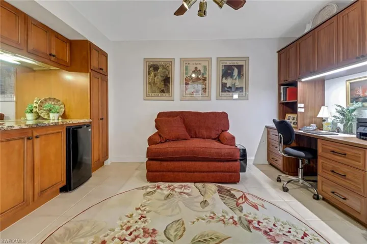 Home office featuring built in desk, ceiling fan, and light tile patterned floors