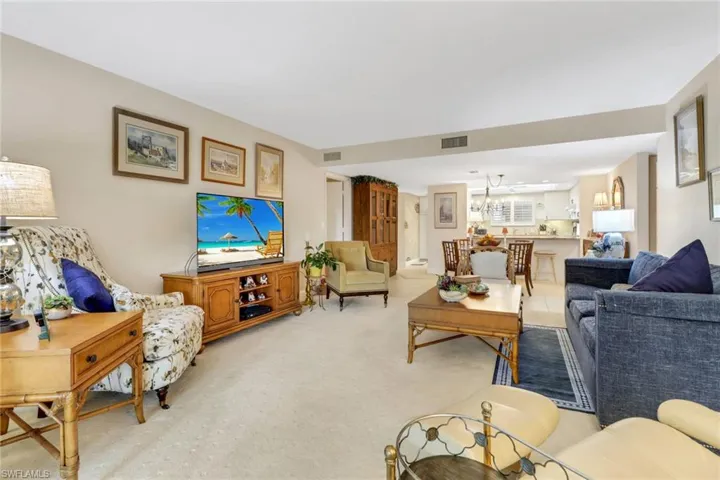 Carpeted living room with a notable chandelier