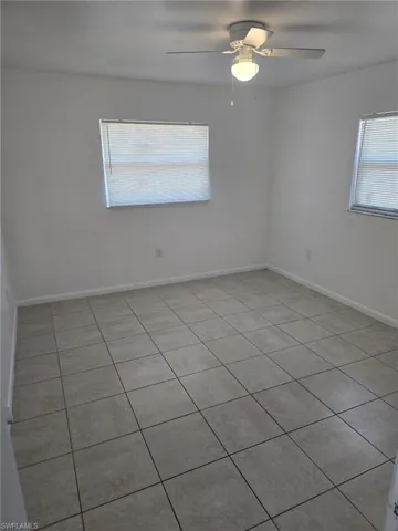 Spare room with ceiling fan, light tile patterned floors, and plenty of natural light