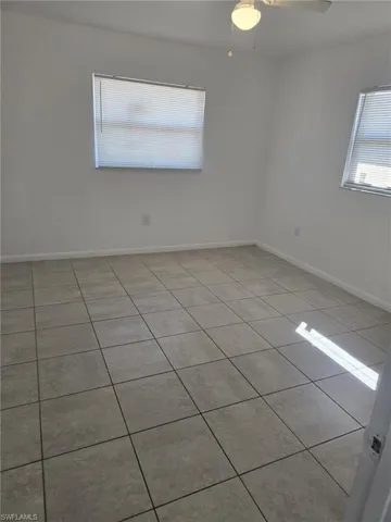 Empty room with light tile patterned floors and ceiling fan