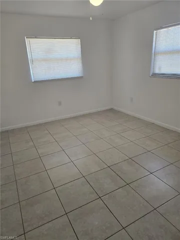 Empty room featuring baseboards and light tile patterned floors
