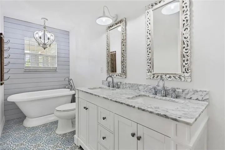 Bathroom featuring tile patterned floors, toilet, a chandelier, and dual bowl vanity
